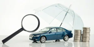 A magnifying glass examines a car, umbrella, and coins for affordable full coverage auto insurance.
